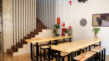 A modern reception area with a wooden reception desk, black metal stools, a staircase with wooden steps, and a white brick wall.