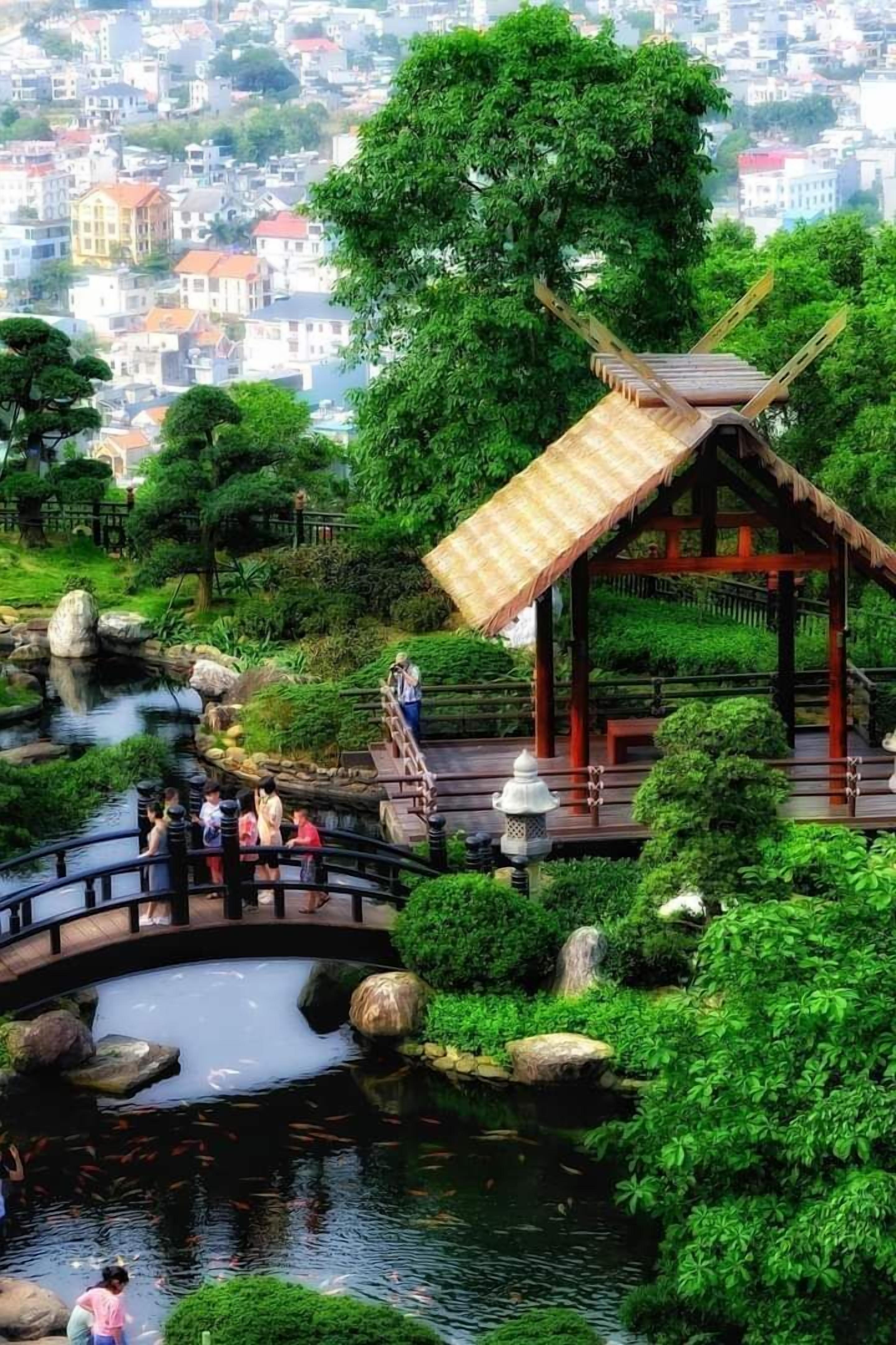 A traditional Japanese garden with a wooden pavilion, koi pond, and a bridge.