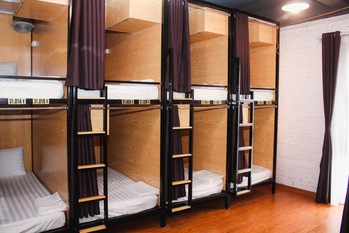 Une chambre de dortoir avec des lits superposés, des murs en bois et un plancher en bois.