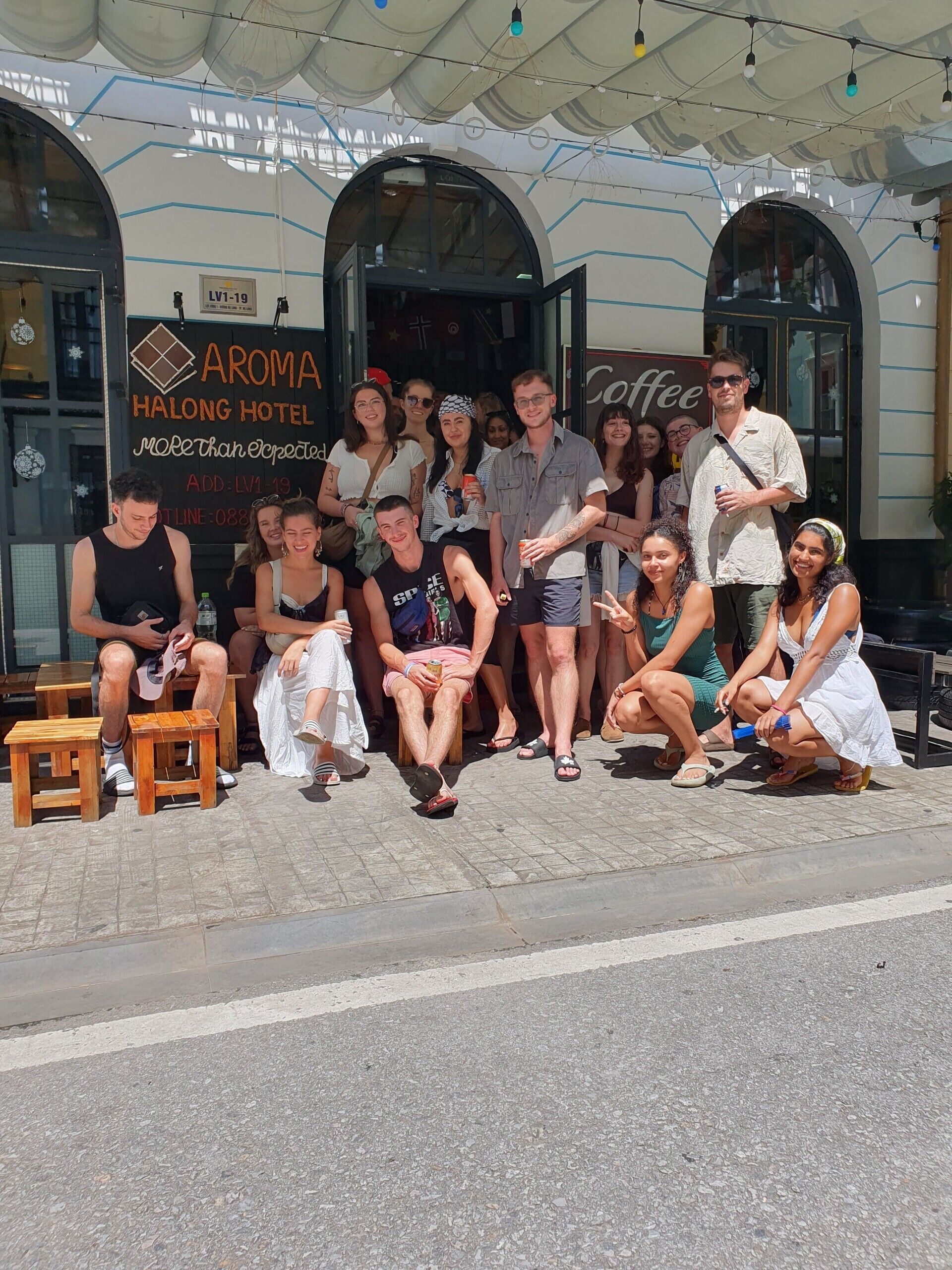 A group of people gathered outside a building with a sign reading "AROMA HALONG HOTEL."