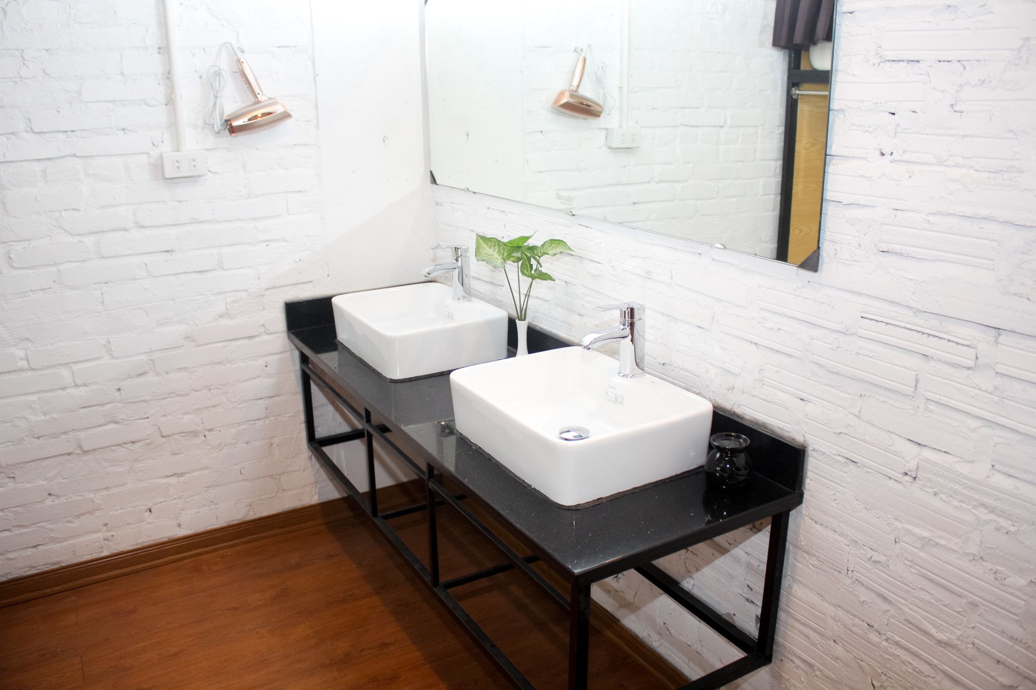 A bathroom with two white sinks, a black countertop, and a mirror.