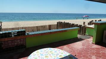 Enjoy ocean views from this beachside patio with a hexagonal tile floor, colorful umbrella, and table with a patterned tablecloth.