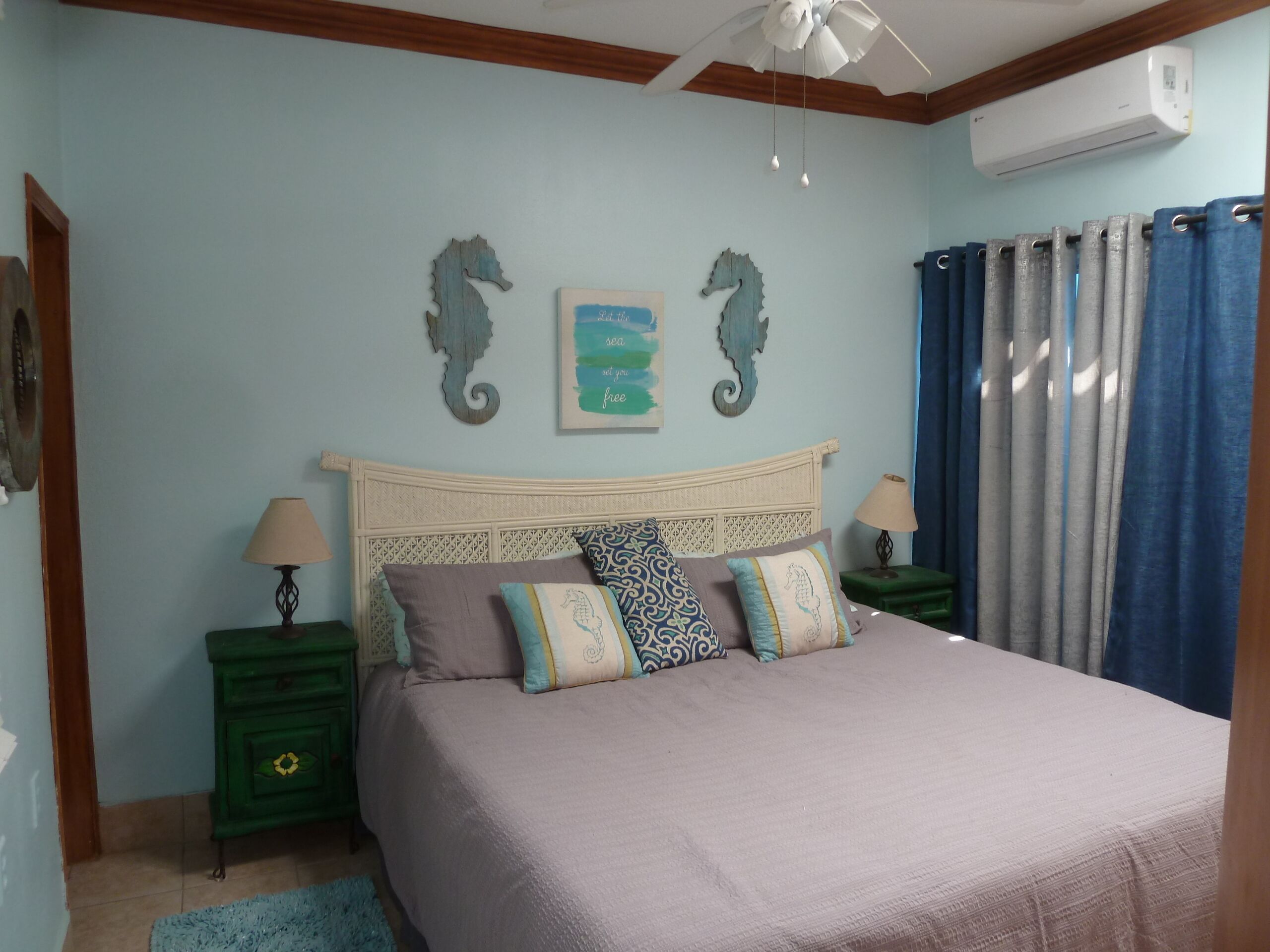 Un dormitorio con una cama, dos mesitas de noche, aire acondicionado de pared y decoración mural.