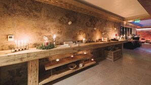 A bar area with a rustic wooden counter, candles, and a stone wall backdrop. - Hotel Cardinal (Vintu de Jos)