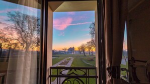 A view from a balcony with a metal railing, overlooking a park with pathways and trees, and a building in the distance. - Hotel Cardinal (Vintu de Jos)