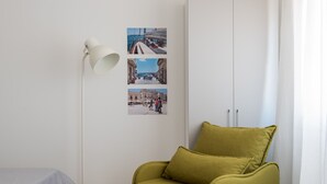 A room with a bed, a green armchair, a white lamp, and a wall with three photographs. - Dioniso Comfort Suite by Wonderful Italy (Siracusa)