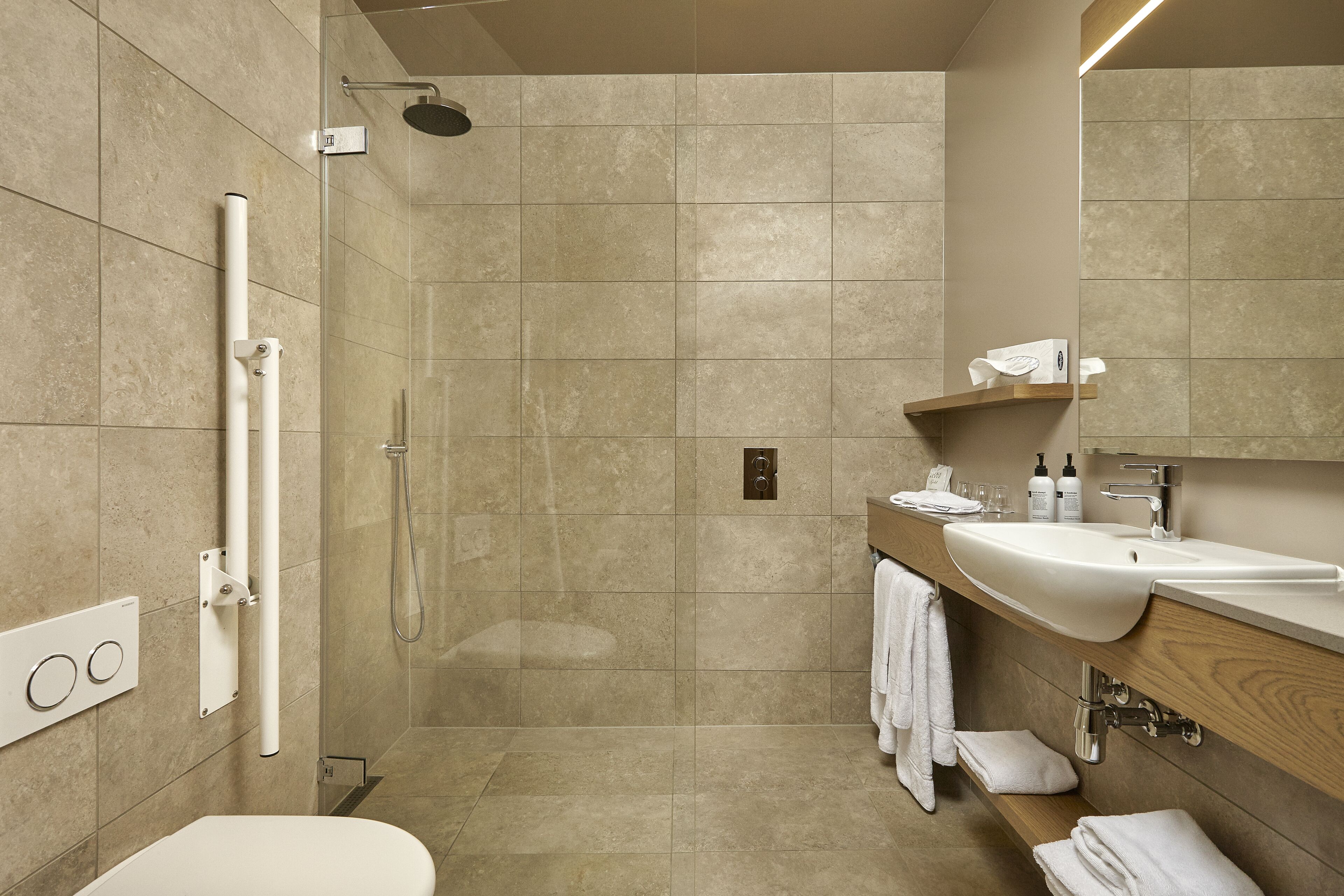 A modern bathroom with a shower, toilet, and vanity with a sink and mirror.