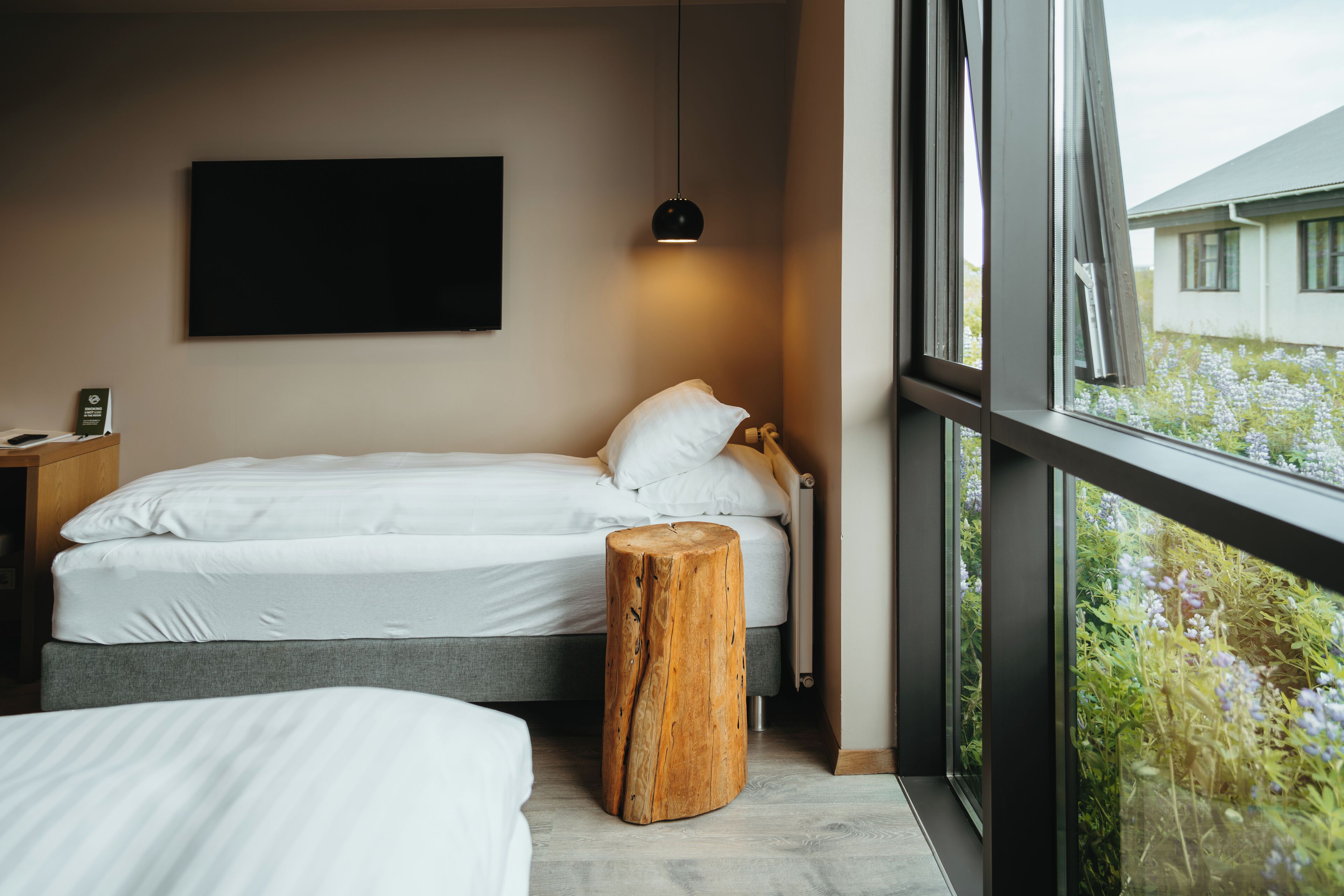 Un dormitorio con cama, mesita de noche y un taburete de madera.
