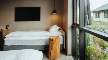 Un dormitorio con cama, mesita de noche y un taburete de madera.