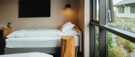 Quarto com uma cama, mesa de cabeceira e um banquinho de madeira.