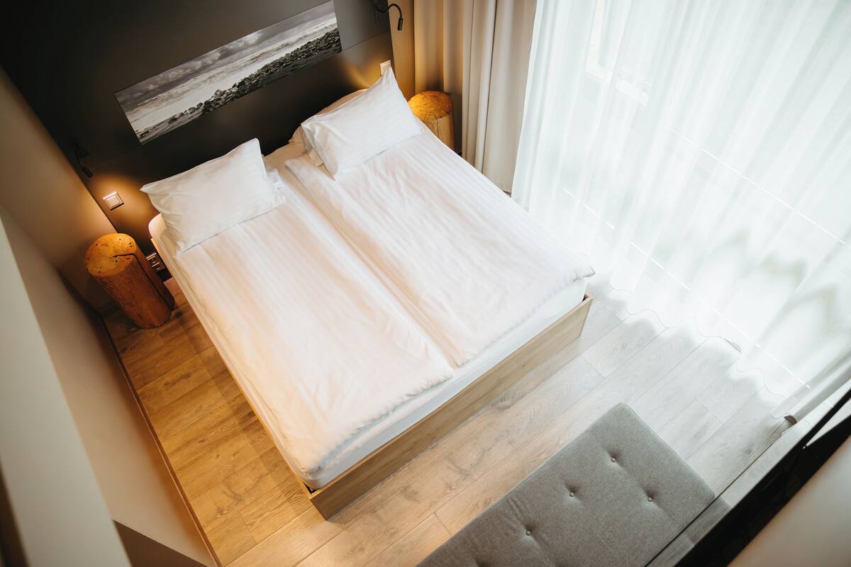 A neatly made bed with white linens in a modern hotel room.
