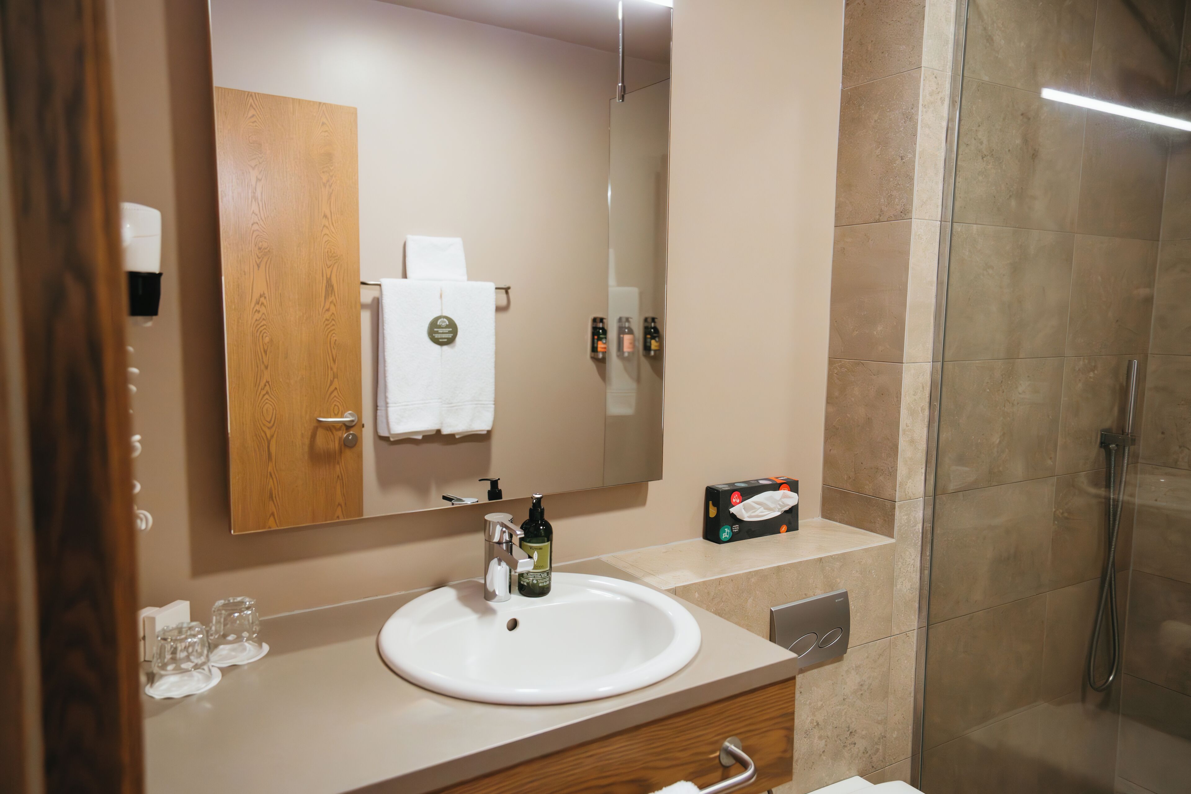 A bathroom with a sink, mirror, and shower.