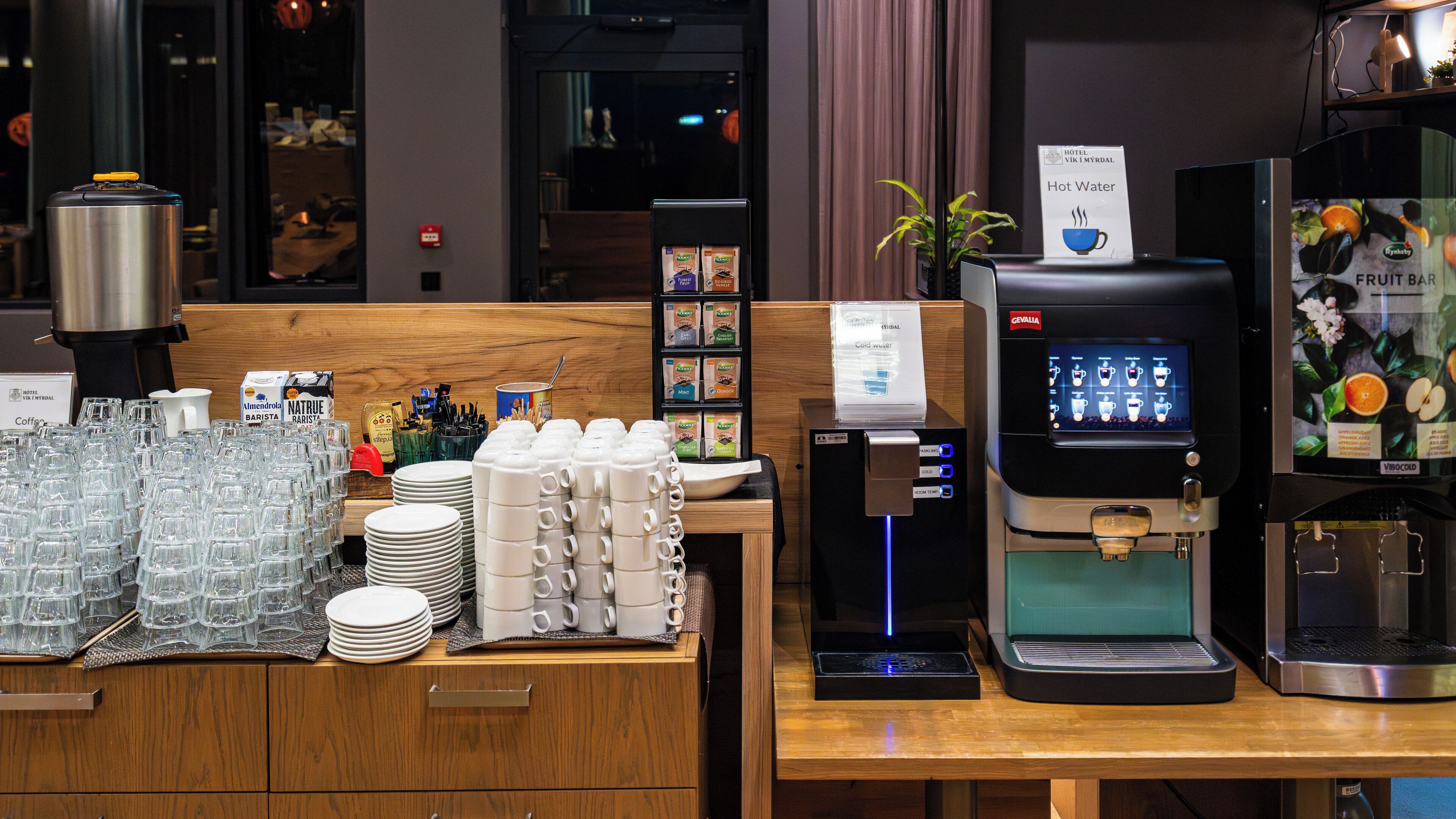 A hotel bar area with a coffee machine, a fruit bar, and various coffee and tea options.