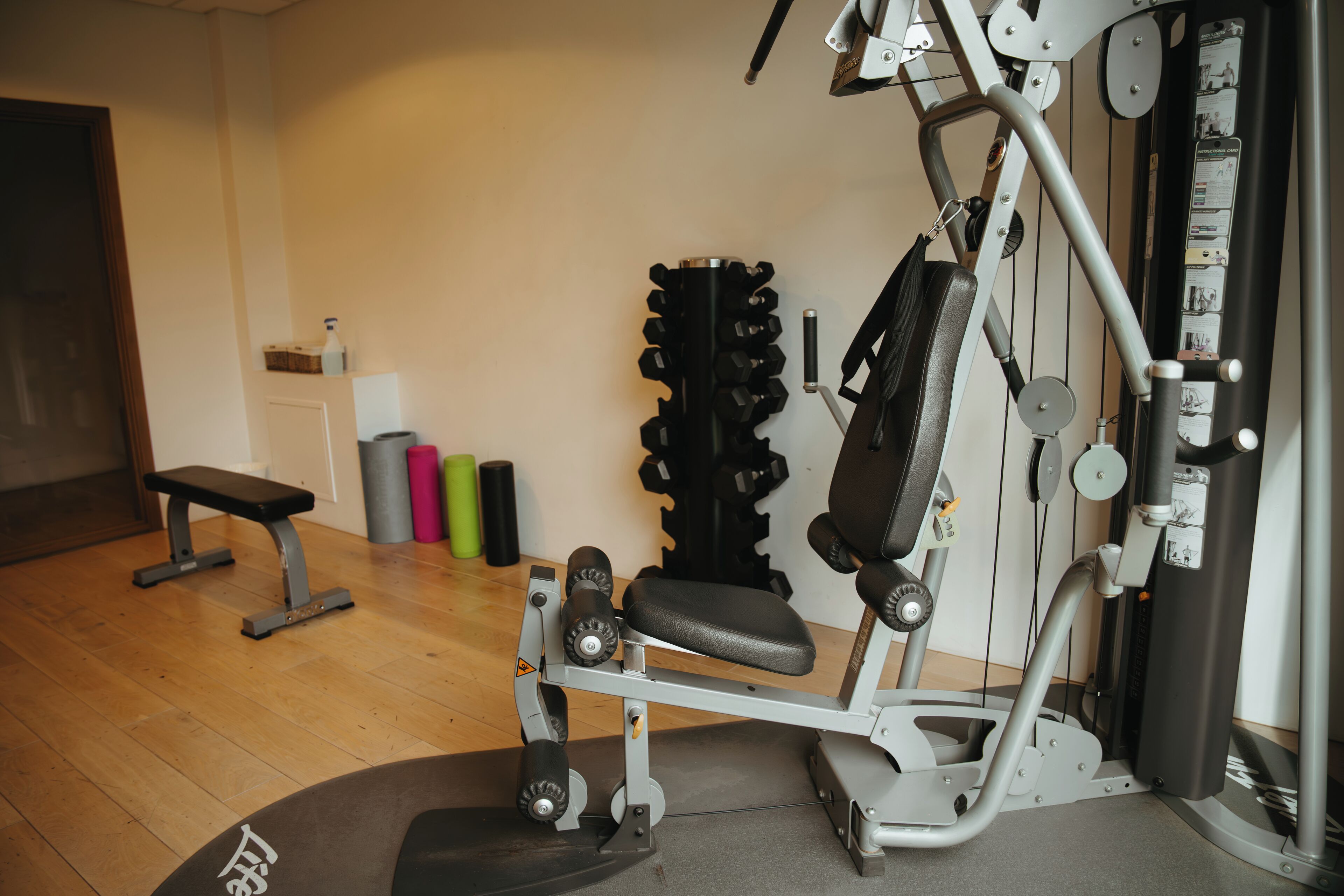 A gym with a bench, weight machine, and various exercise equipment.
