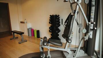A gym with a bench, weight machine, and various exercise equipment.
