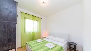 A bedroom with a bed, a nightstand, a lamp, and a window with curtains. - 1 bedroom awesome apartment in Okrug Donji (Okrug Donji)