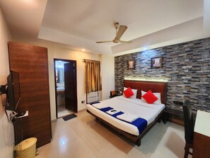 Ein Hotelzimmer mit Bett, Deckenventilator, Steinwand und Holzt ür.