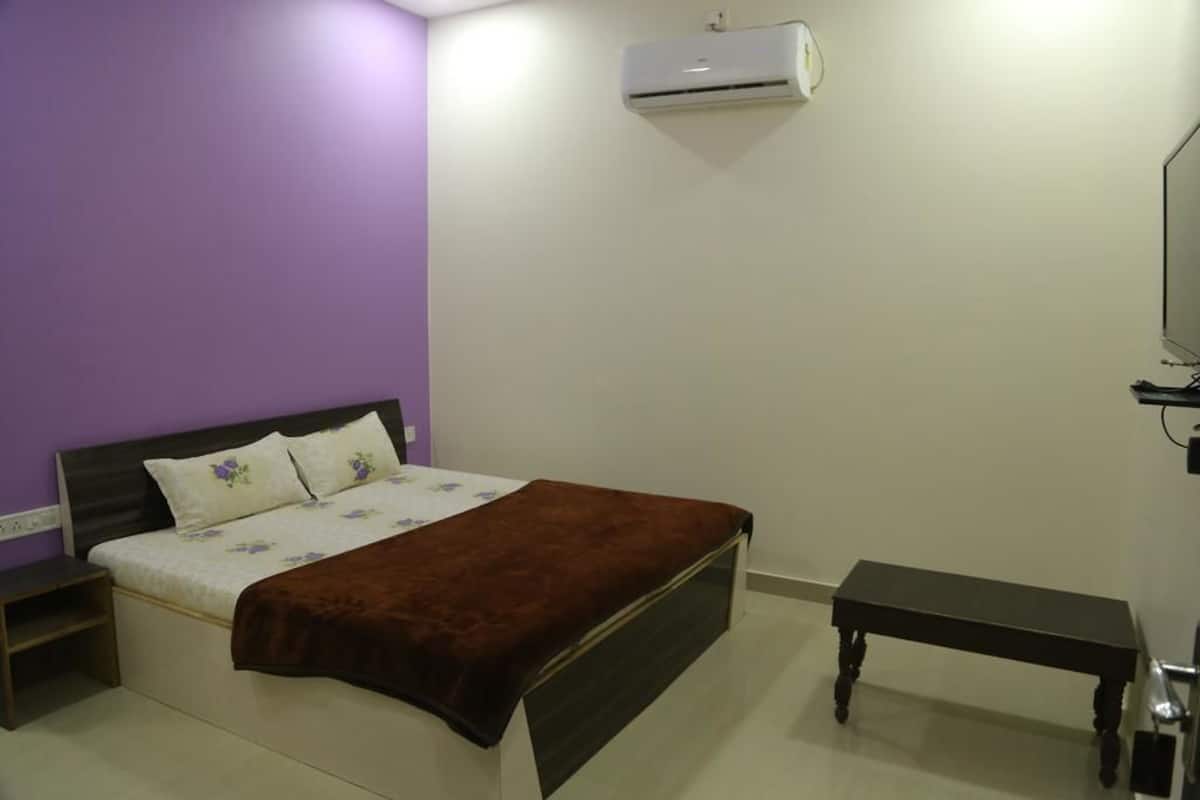 Un dormitorio con cama, mesitas de noche, un banco y un equipo de aire acondicionado.