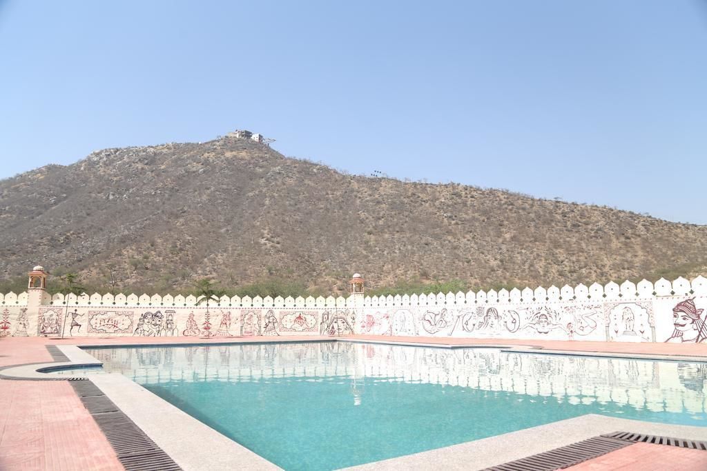 Una piscina con cerca decorativa blanca y una montaña al fondo.
