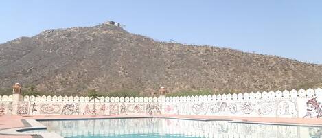 A swimming pool with a white decorative fence and a mountain in the background.