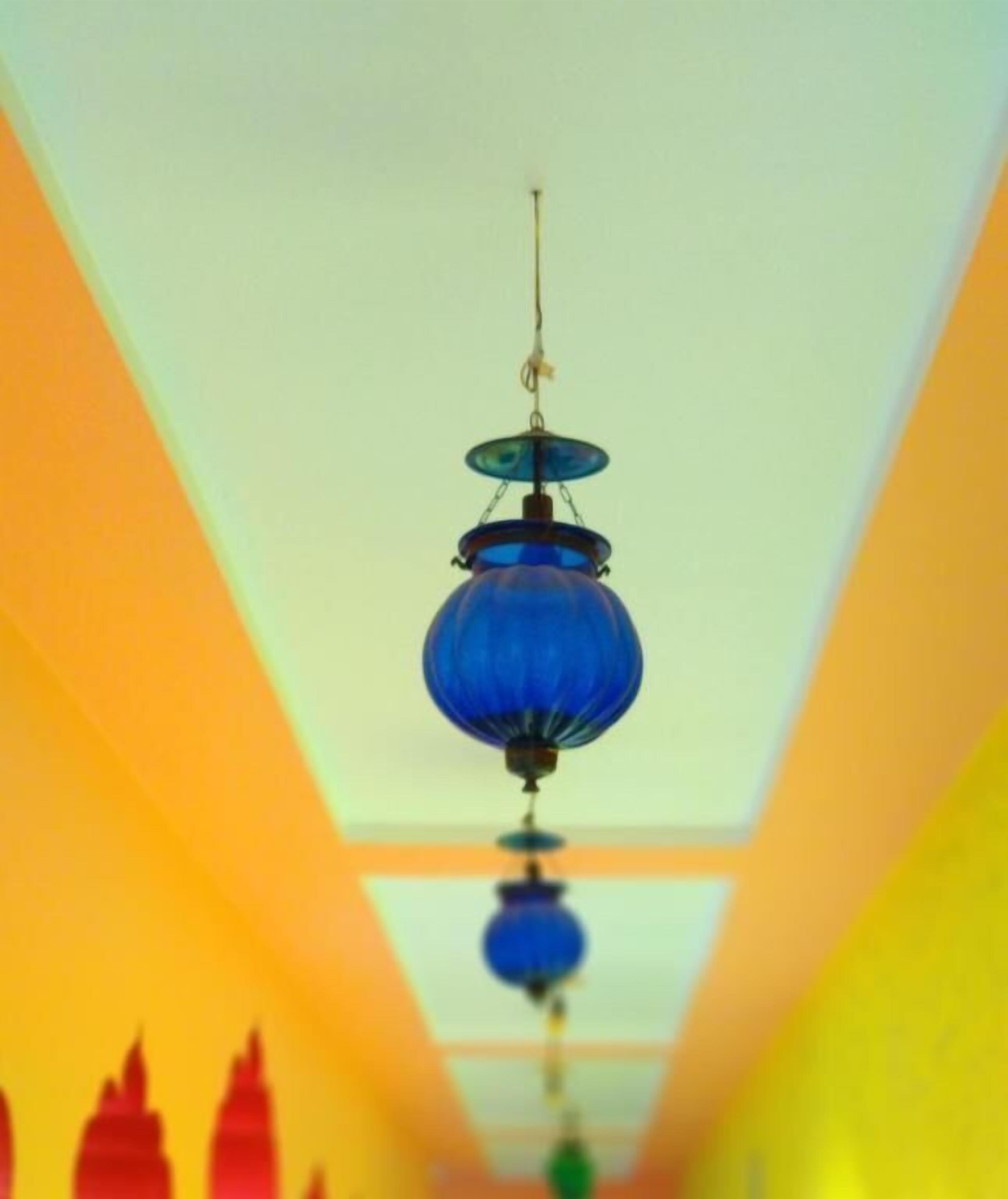 A hallway with a series of blue hanging lamps.