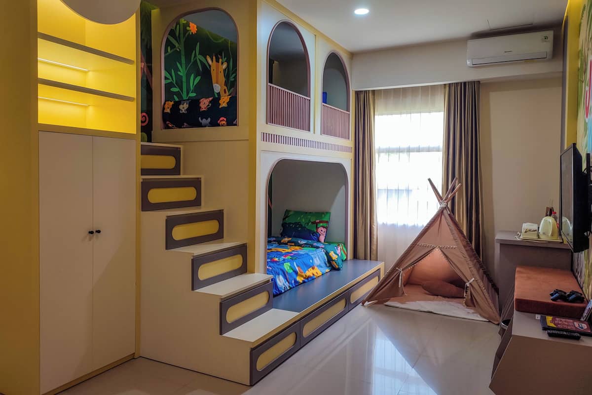 Une chambre d’enfant avec des lits superposés, un espace de jeux et une tente.