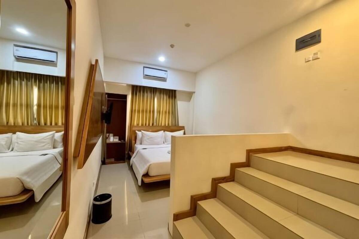 Une chambre d’hôtel avec deux lits, un escalier et un appareil de climatisation.
