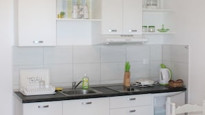 Uma cozinha moderna com armários brancos, bancada preta e piso de madeira.