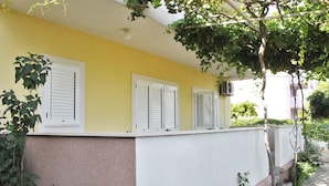 Um edifício amarelo com persianas brancas e uma parede branca.