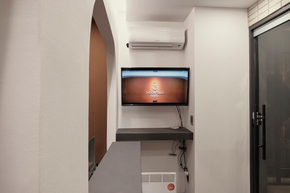 A hotel room with a flat-screen TV mounted on the wall displaying 'The Capsule Hotel' branding. - THE CAPSULE Myeongdong (Seoul)