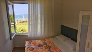 A bedroom with a bed, a window with curtains, and a view of the sea. - Ergul Apart Hotel (Kandira)