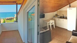 A balcony with a view of the sea, a small kitchen with a sink and stove, and a dining area with chairs. - Ergul Apart Hotel (Kandira)