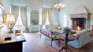 Un salon spacieux avec une cheminée, un canapé, une table à manger et un lustre.