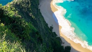 Un paisaje costero con una formación rocosa destacada y una playa estrecha.