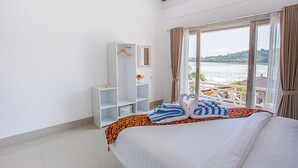 Habitación de hotel con cama, armario, ventana con vista al mar y balcón con mobiliario exterior.