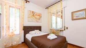 Une chambre à coucher avec un lit, des rideaux, un tableau et une fenêtre.