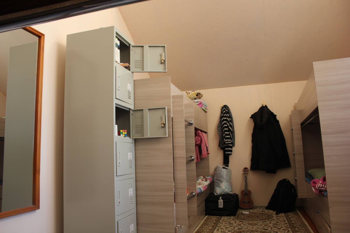 A compact bedroom with a wardrobe, a guitar, and a suitcase.