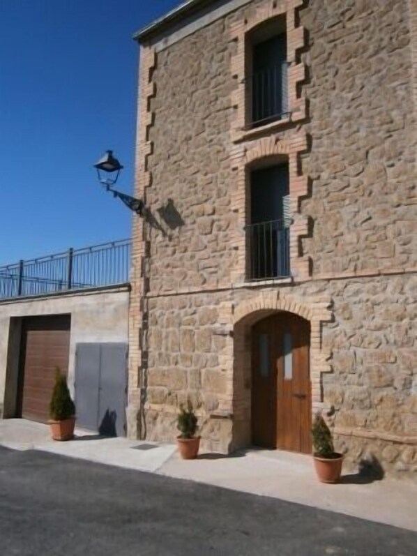 A stone building with a wooden door, a window, and a balcony. - Casa Cal Fuster for 5 people (Pinell de Solsonès)