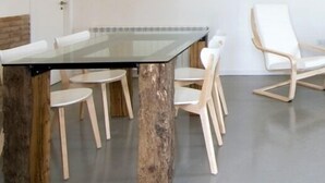 Een moderne eetruimte met een tafel met glazen blad en houten stoelen.
