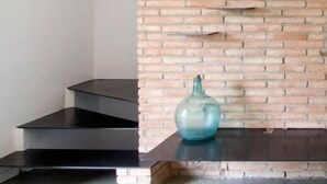 Een modern interieur met een bakstenen muur, een donkere vloer en een blauwe vaas op een plank.