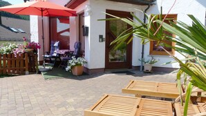 A patio area with wooden loungers, a red umbrella, and potted plants. - Ferienhaus & Nurdachhaus Rothaargebirge (Bad Berleburg)