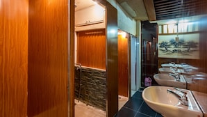 Un baño moderno con paredes de madera, una zona de ducha de piedra y varios lavamanos.