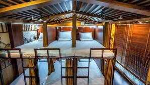 Una cabaña con dos camas, vigas de madera, un mural y vistas a través del ventanal.