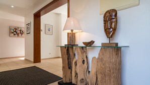 A reception area with a wooden console table, a lamp, and a wooden sculpture. - Outstanding apart with pool view & terrace at Vila Sol (Quarteira)