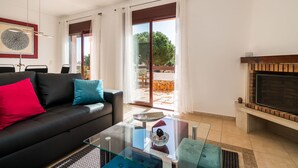 A modern living room with a sofa, a glass coffee table, and a fireplace. - Outstanding apart with pool view & terrace at Vila Sol (Quarteira)