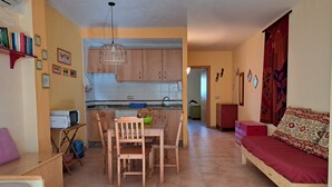 Ett kompakt bostadsutrymme med en matplats, ett litet kök och en soffa.