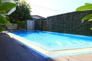 Una piscina al aire libre, sillones reclinables de piscina