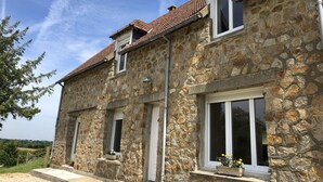 A stone building with a tiled roof, multiple windows, and a small balcony.