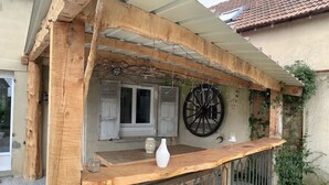A rustic wooden outdoor seating area with a table, a vase, and a wine glass.