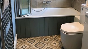 Et badeværelse med bruser, badekar og toilet.